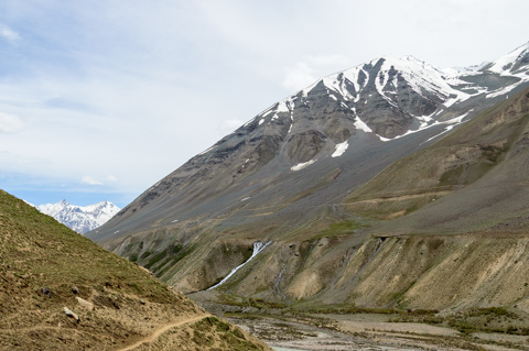 The Pin River flows through a wide, rocky valley beneath steep, snow-streaked Himalayan mountains in Pin Valley, Himachal Pradesh, India.