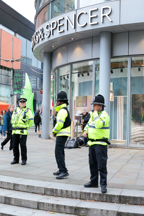 Police officers stand outside a Marks & Spencer store in Manchester, England, monitoring a peaceful protest in the city center.