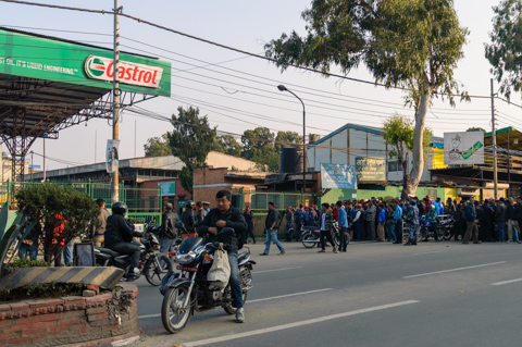 Drivers and motorbike riders line up outside a petrol station in Kathmandu, Nepal, as security forces monitor queues during fuel shortages in November 2015.